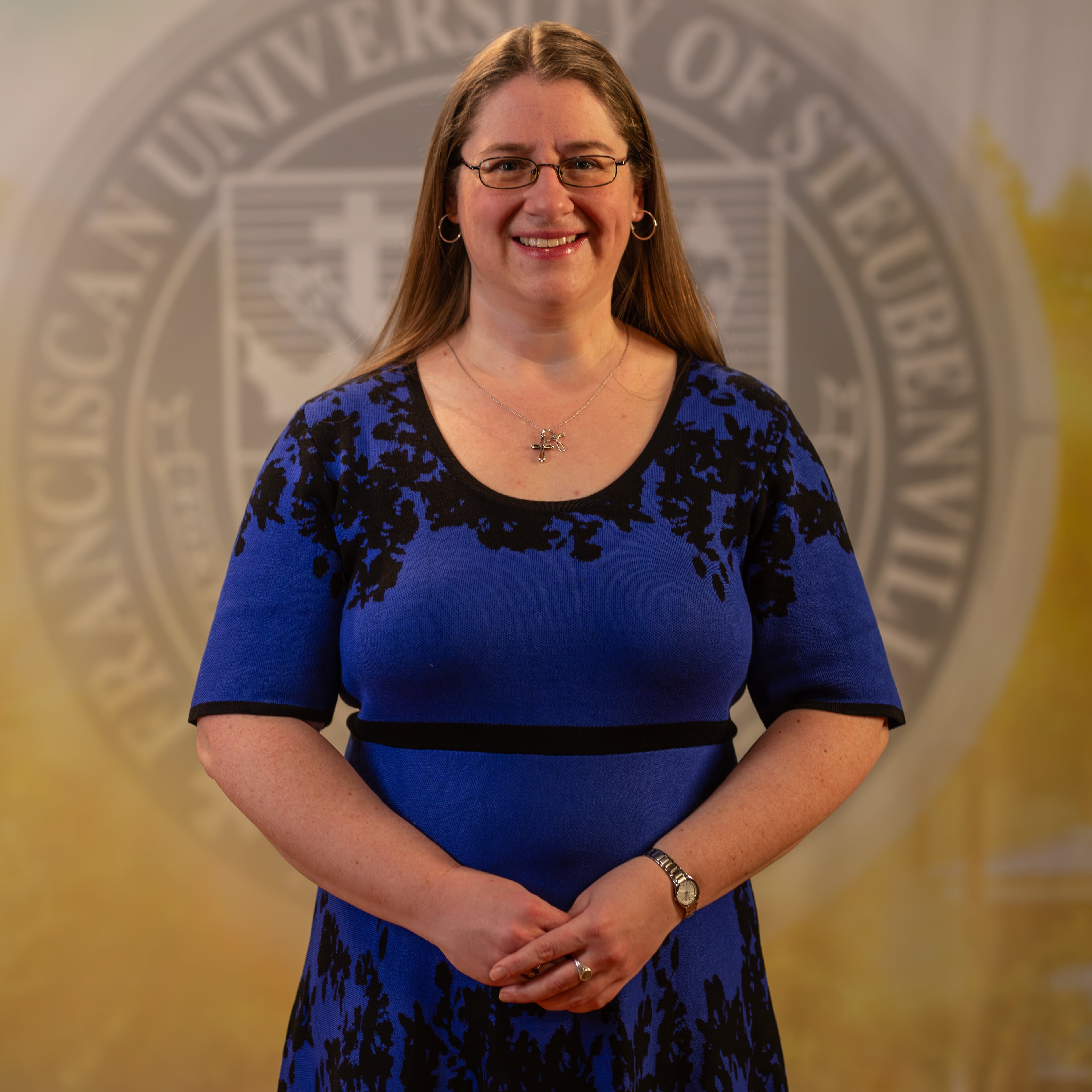 Alicia Boyle standing in front of a university seal.
