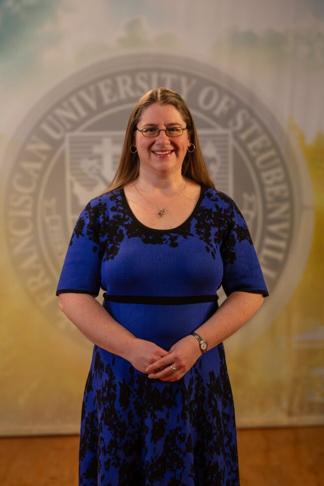 Alicia Boyle standing in front of a university seal.
